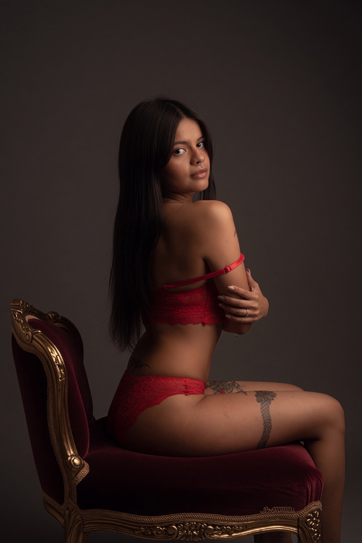 Lia Hancock seated in red lingerie